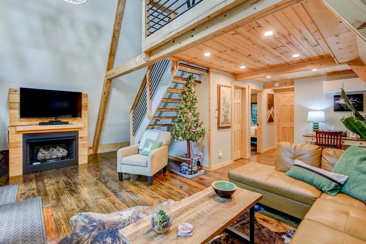 Inside, the inviting living room features a fireplace, a comfortable sofa, a TV for movie or sports nights, and a decorative tree, creating a warm atmosphere for family relaxation and bonding. The open space is perfect for gathering after a fun-filled day outside.
