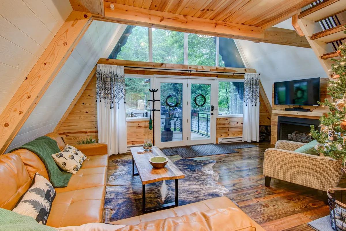 A stylish living room with a plush leather sofa, wooden coffee table, warm fireplace, and expansive windows that fill the space with natural light. The inviting arrangement is perfect for relaxation, gathering with family, or enjoying entertainment by the fire.